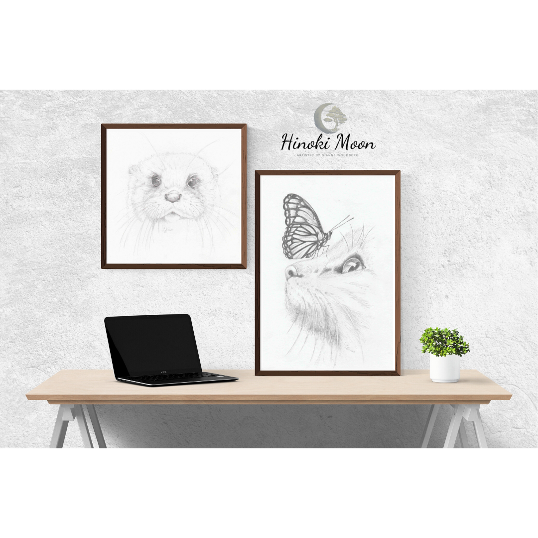 Desk with framed pencil drawings of otter face and cat profile